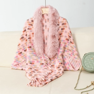 Detail of pink knitted shawl with plush faux fur collar and fringe hem on wooden hanger