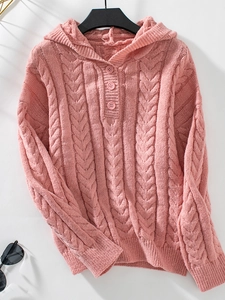 Close-up of pink cable knit texture and button details on a thick hooded sweater