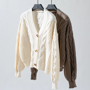 Detailed view of chunky cable-knit pattern and amber buttons on a V-neck cardigan