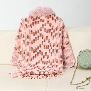 Close-up of pink knitted shawl with faux fur collar and geometric pattern detail