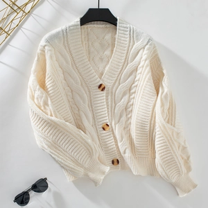 Detailed macro view of cream cable knit texture and vintage buttons on the cardigan