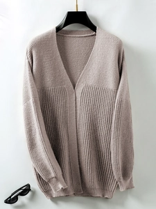 Detail of V-neck knitted cardigan showing chunky rib knit texture and soft mauve color