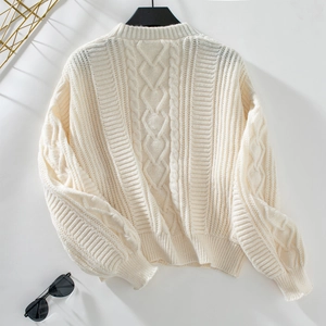 Close-up of cream cable knit texture and ribbed cuff detail on retro cardigan