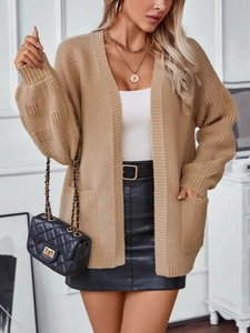 Close-up of geometric jacquard knit texture and large pocket on a camel cardigan