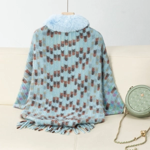 Detail of light blue knit poncho with faux fur collar and geometric patterns