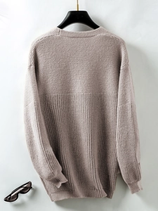 Close-up of brown knit sweater texture with ribbed cuffs and drop shoulder detail