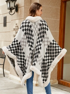 Outdoor shot of a women's black and white checkered poncho with faux fur collar trim