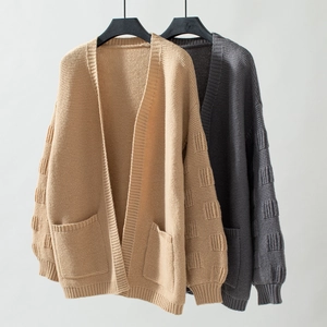 Detail of waffle knit textured sleeves and front pockets on long knit cardigan