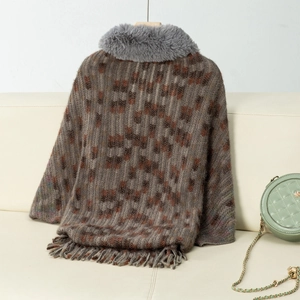 Close-up of knit poncho featuring grey faux fur collar and decorative fringe details