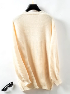 Detailed close-up of cream chunky knit texture and pattern on long cardigan