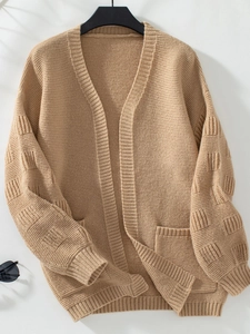 Close-up of beige knit cardigan texture with detailed ribbed pockets and V-neck design