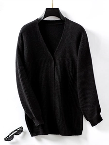 Close-up of black knitted cardigan showing thick ribbed texture and V-neckline detail