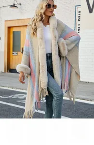 Détail d'un poncho à capuche en tricot avec rayures colorées, fausse fourrure et franges