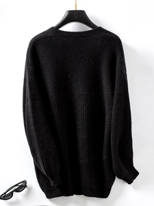 Detailed close-up of chunky black knit sweater showing ribbed cuffs and texture