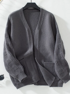 Detail of chunky knit dark grey cardigan featuring textured block sleeves and ribbed cuffs