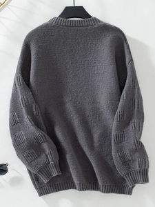 Close-up of dark grey knit cardigan showing detailed square textured patterns on sleeves