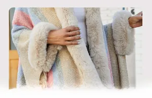 Détail de la bordure en fausse fourrure douce sur le poncho en tricot à rayures colorées