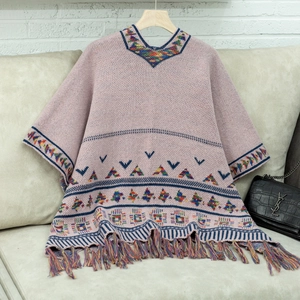 Detail eines rosa Strickponchos mit ethnischen Jacquardmustern und bunten Fransensäumen