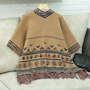 Detail eines kamelfarbenen Strickschals mit geometrischem Jacquardmuster und bunten Fransen