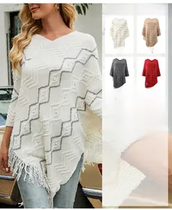 Close-up of knit poncho featuring grey wavy patterns, fringe edges, and pearl accents