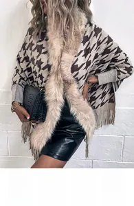 Dettaglio poncho in maglia con motivo pied de poule, bordo in pelliccia e nappe
