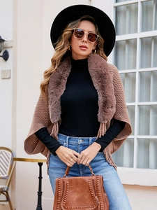 Detailed view of brown knit poncho featuring a plush faux fur collar and fringe tassels