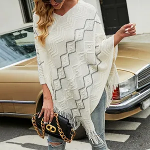 Beige knit poncho with wavy stripes and pearl accents on urban street background