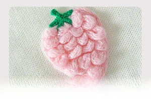 Close-up of 3D knit strawberry pattern with soft pink wool texture on sweater fabric