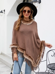 Detail of brown knitted poncho featuring thick faux fur trim and long tassel accents