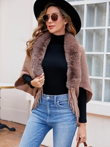 Close-up of tan knit shawl with thick faux fur collar and long fringe tassel detail