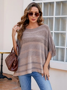 Close-up of knit poncho featuring earth-tone gradient stripes and long fringe tassels