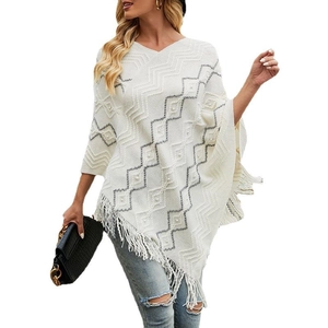Women's white knitted poncho with wave pattern, pearl accents, and fringe tassels