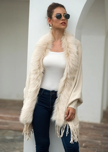 Detail of beige knit shawl featuring a lush faux fur collar and long fringe tassels