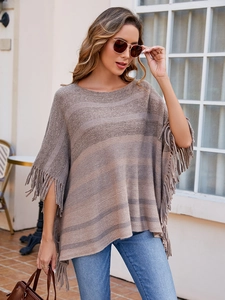 Detail of bohemian knit poncho featuring earth-toned stripes and long fringe tassels