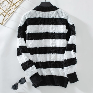 Détail de la maille torsadée à rayures noires et blanches sur un pull ample à col rond