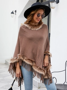 Detail of brown knitted poncho featuring faux fur collar and long fringe tassels