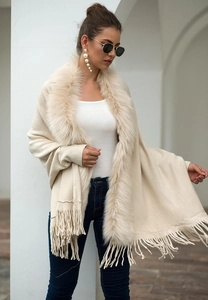 Detail of elegant beige knitted shawl with faux fur collar and long tassel hemline