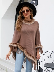 Detail of knitted poncho featuring brown faux fur trim and elegant fringe hem tassels