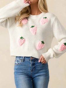 Detailed close-up of 3D pink strawberry embroidery on white knitted sweater fabric