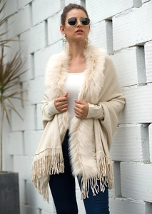 Close-up of knit shawl detailing elegant faux fur collar and long fringe trim design