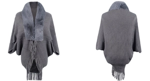 Macro view of grey knit poncho featuring a plush faux fur collar and fringe tassels