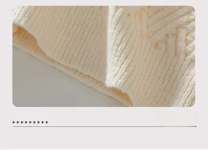 Detail of cable knit texture and ribbed hem on a cream white chunky knit sweater