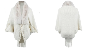 Detail of beige knit poncho with faux fur collar and fringe trim showing diamond pattern