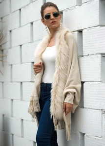 Detail of knit shawl featuring cream faux fur collar and long tassel hemline