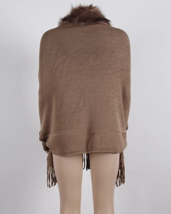 Detail of knit cape with brown faux fur collar and long tassel fringe on the hemline