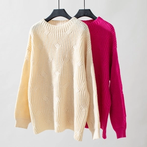 Detail of cable knit pattern on loose long-sleeve sweaters in beige and rose pink