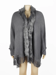 Detail of dark grey knit poncho featuring a soft faux fur collar and long tassel hemline
