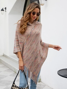 Detail of hooded knit poncho showing beige rainbow yarn texture and soft fringe trim