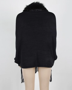 Detail of black knitted poncho featuring a plush faux fur collar and long fringe trim