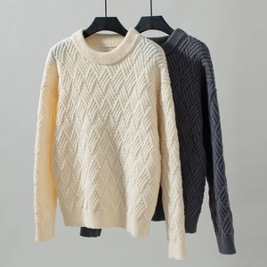 Detailed close-up of cable knit patterns on cream and dark grey crew neck sweaters